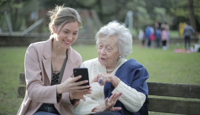 امرأة شابة وامرأة عجوز تنظر إلى هاتف على المقعد