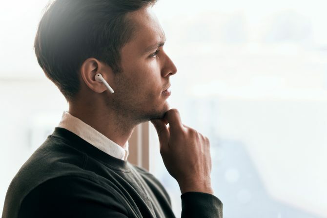 رجل يفكر بينما هو خارج النافذة وهو يرتدي السماعات اللاسلكية في سماعات الأذن